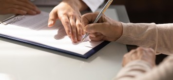 Hands of woman filling document in office. 
