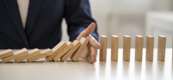 Businesswoman stopping wooden blocks falling down