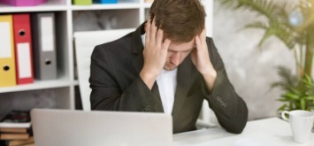 man feels tired and annoyed sitting at his working place in office 