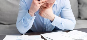 Distressed young man sit at desk paying bills feel stressed having financial problems.