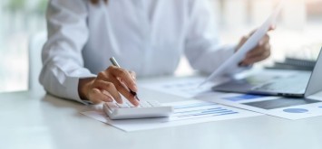 Close-up of businesswoman hands using a calculator to check company finances and earnings and budget