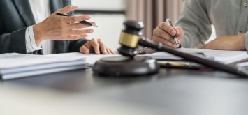Lawyer Legal counsel presents to the client a signed contract with gavel and legal law.