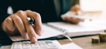 Investors are calculating on calculator investment costs and holding cash notes in hand.