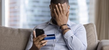 Stressed man with credit card and phone