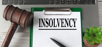 INSOLVENCY - word on a white sheet on the background of a laptop, a court hammer and a pen. Business concept