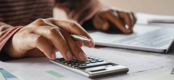 Business woman using calculator and laptop in office