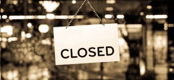 A closed sign hanging in a shop window with retro effect filter.