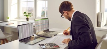 Male bookkeeper working with financial report in in office.