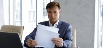 Focused mature company executive reviewing a document.