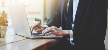 Professional businessman in black suit working on new project with notebook computer.