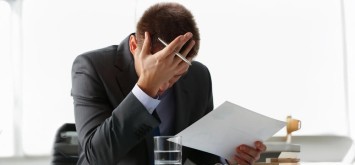 Close-up of adult man businessman hold paper sheet in hand and close face with palm.